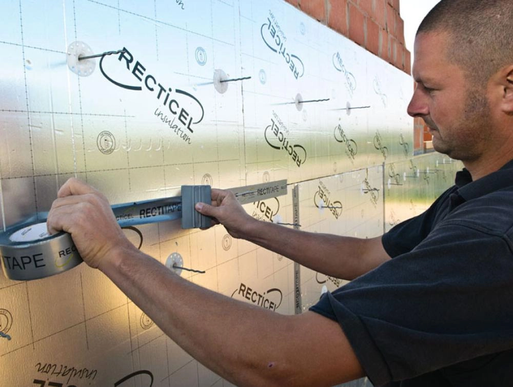 Pose d'une bande d'aluminium Rectitape pour assurer l'étanchéité des panneaux PIR Recticel.